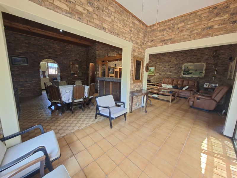 Spacious open-plan living and dining area featuring rustic exposed brick walls, tiled flooring, and a built-in bar, offering a warm and character-filled interior space.