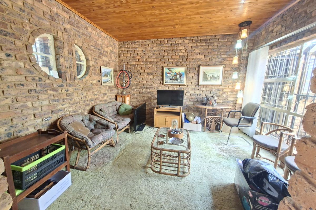 A living room featuring exposed brick walls, a timber ceiling, and circular feature windows, offering a rustic aesthetic with potential for modern updates.