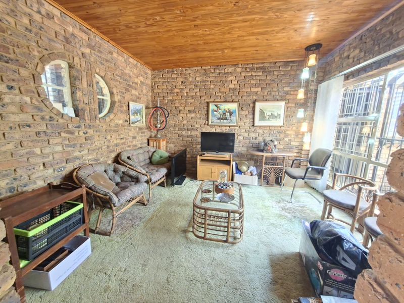A living room featuring exposed brick walls, a timber ceiling, and circular feature windows, offering a rustic aesthetic with potential for modern updates.