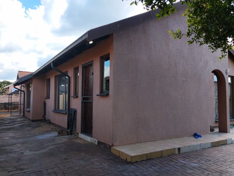 Side view of a residential property featuring a paved driveway, security gate, and exterior wall finishes.