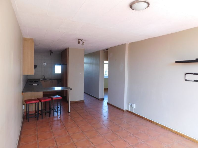 Open-plan living and kitchen area featuring tiled flooring, built-in cabinetry, and a breakfast counter, offering a functional layout for modern living.