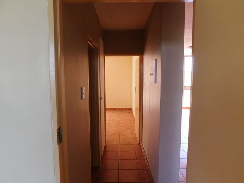 A functional hallway connecting interior spaces, featuring tiled flooring and neutral wall finishes, providing access to adjacent rooms within the flat.