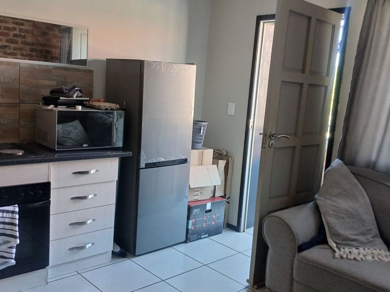 Open plan kitchen and living area featuring tiled flooring, built-in cabinetry, and an integrated oven with hob, providing a functional living space.
