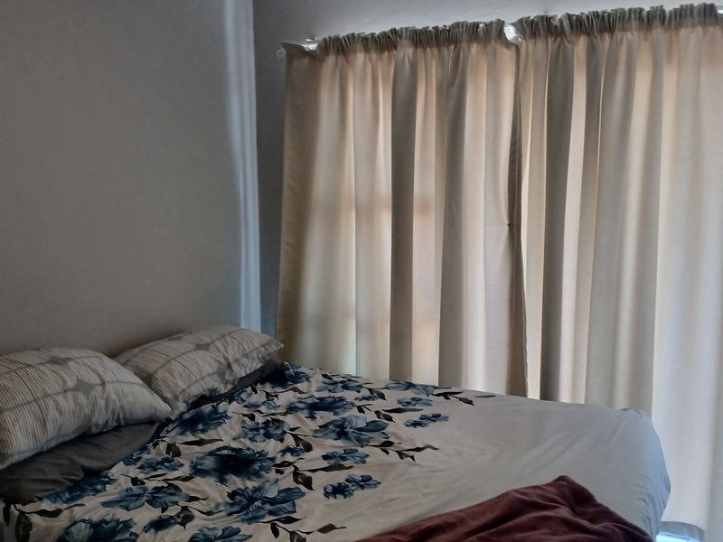 A bedroom featuring a sliding glass door with curtains, providing natural light and access to an outdoor area.