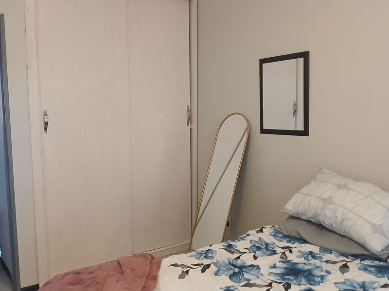 A bedroom featuring a built-in sliding door wardrobe with light wood-grain finish and neutral wall tones.