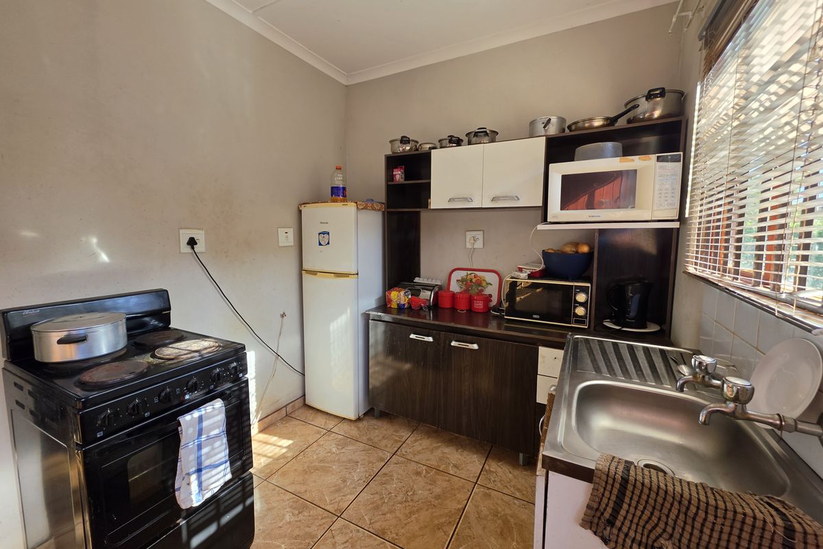 Compact kitchen featuring tiled flooring, built-in cabinetry, a stainless steel sink, and a freestanding stove, offering a functional layout with potential for modernization.