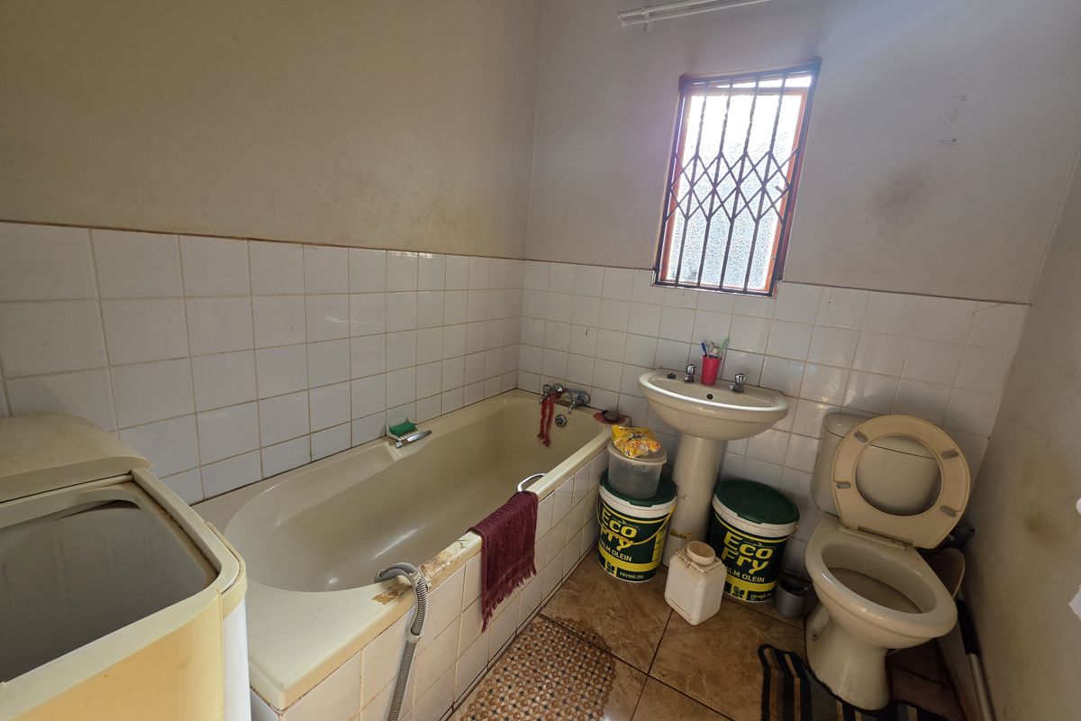 A dated bathroom featuring a bathtub, pedestal basin, and toilet, requiring cosmetic updates and refurbishment to improve its overall condition and appeal.