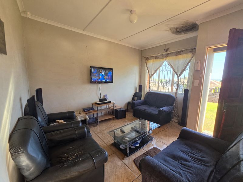 A living room featuring tiled flooring and security bars on the window, currently showing signs of ceiling water damage and wall wear.