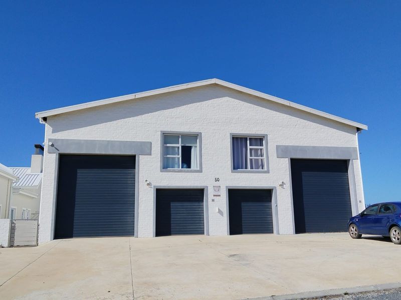 Front elevation of a modern property featuring a painted brick facade, four roller shutter garage doors, and a spacious concrete driveway.
