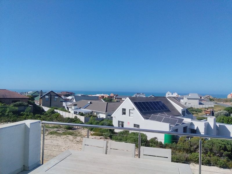 Elevated coastal view overlooking the surrounding residential neighbourhood and ocean horizon, featuring a modern stainless steel and cable balustrade.