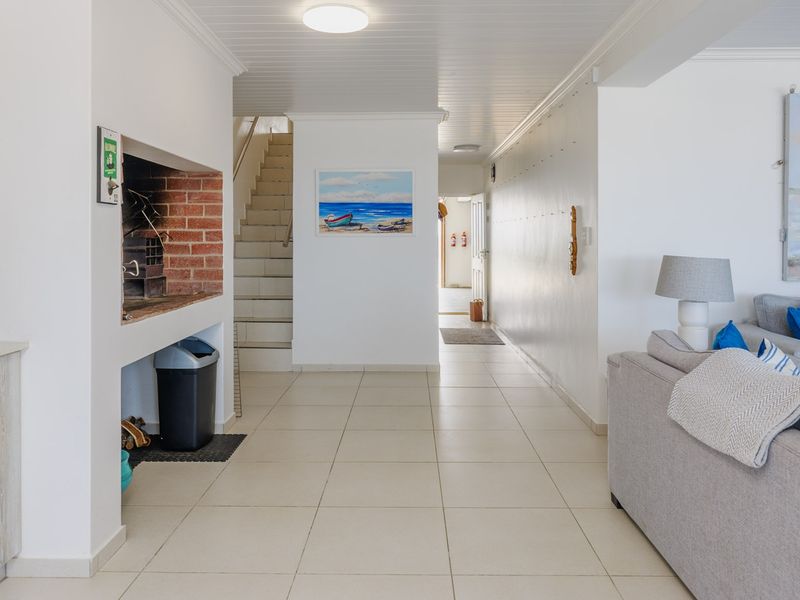 Open plan living area featuring a built-in indoor braai, tiled flooring, and a staircase leading to the upper level.