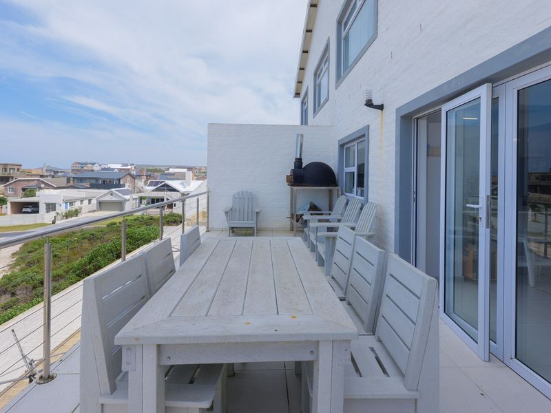 Spacious elevated balcony featuring tiled flooring, a built-in pizza oven, and stainless steel balustrades, offering expansive views of the surrounding neighborhood.