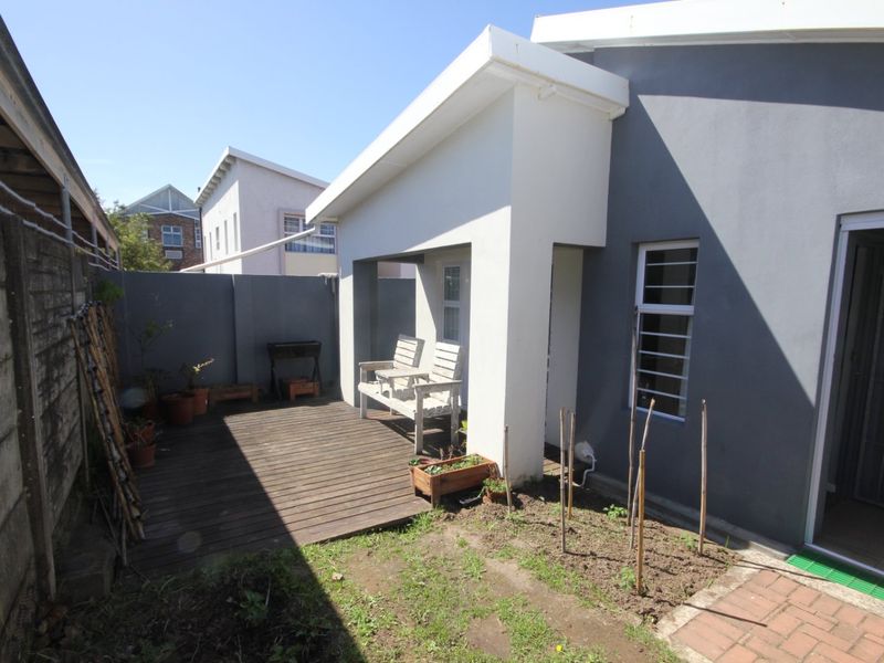 A private rear patio area featuring timber decking, a covered section, and direct access to the townhouse interior.