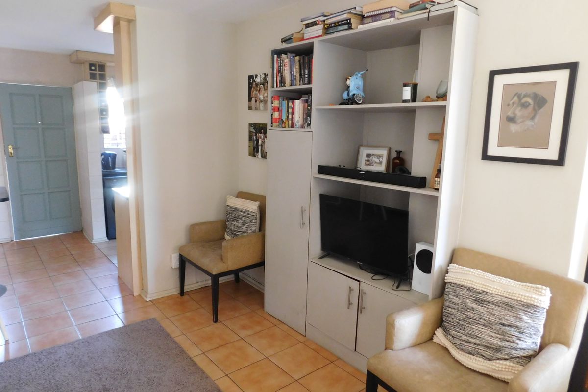 A living area featuring tiled flooring and a built-in shelving unit, with an adjacent doorway leading to another section of the townhouse.