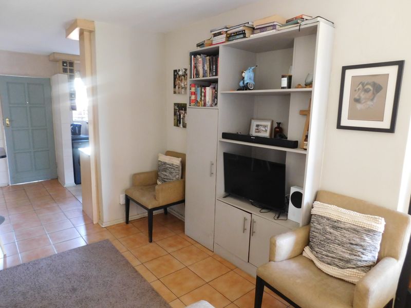 A living area featuring tiled flooring and a built-in shelving unit, with an adjacent doorway leading to another section of the townhouse.