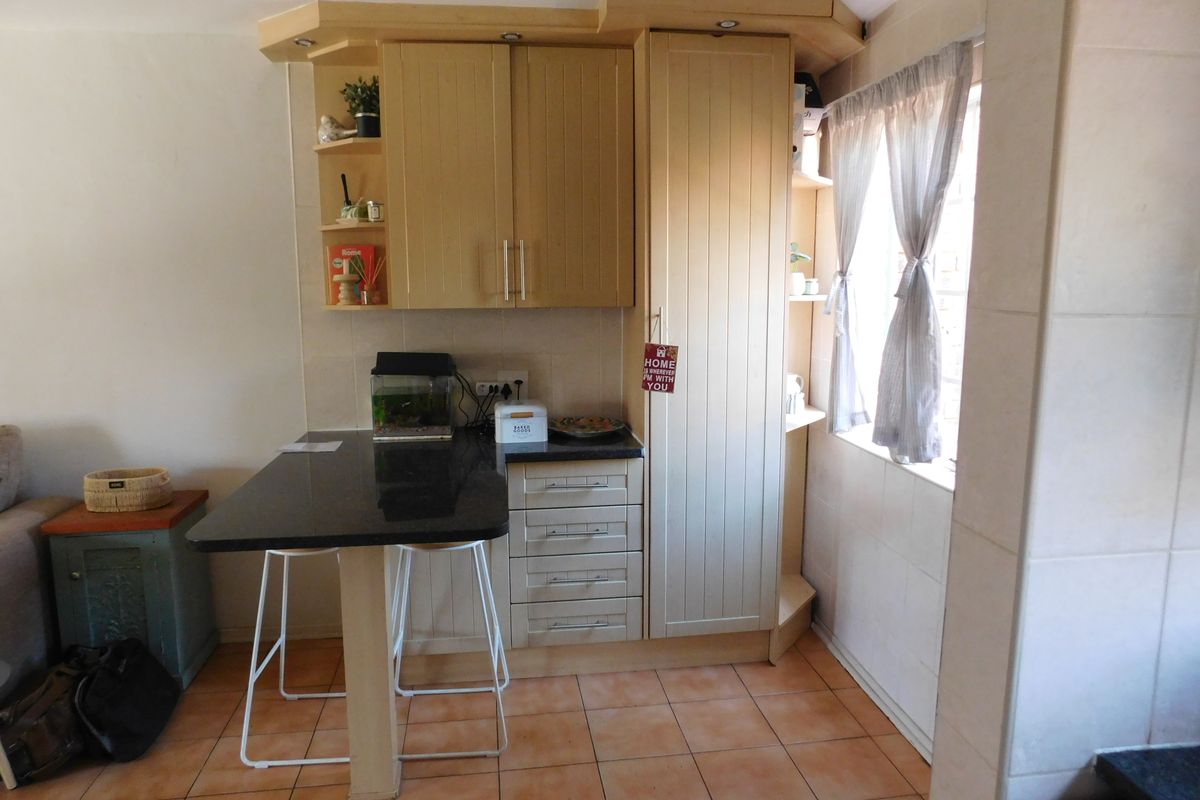 A compact kitchen area featuring light-toned built-in cabinetry, a dark granite breakfast bar, and tiled flooring, offering a functional and efficient workspace.