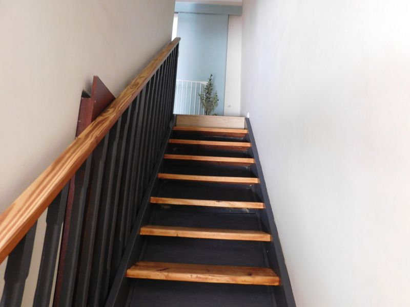A staircase featuring wooden treads and a dark metal balustrade with a wooden handrail, leading to an upper landing area.