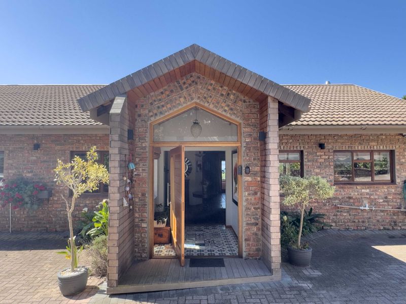 A charming front entrance featuring a gabled brick porch, timber door, and paved driveway, showcasing classic architectural character and well-maintained exterior finishes.