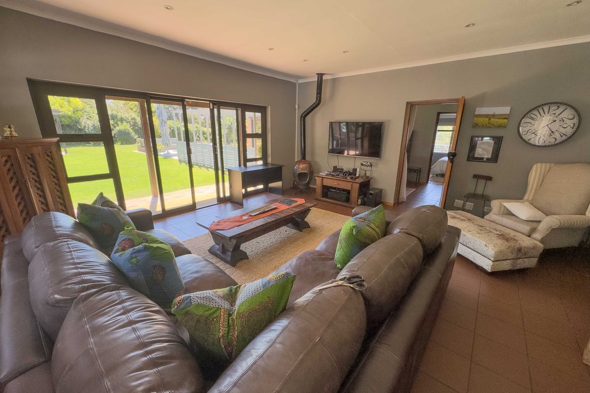 Spacious living room featuring a freestanding fireplace, tiled flooring, and large sliding glass doors that provide direct access to the garden.