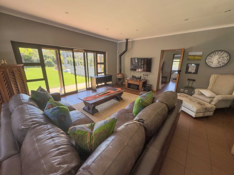Spacious living room featuring a freestanding fireplace, tiled flooring, and large sliding glass doors that provide direct access to the garden.
