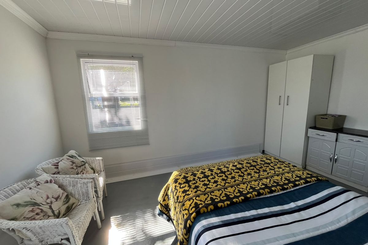 A bedroom featuring a built-in wardrobe, tongue and groove ceiling, and venetian blinds, offering a functional space with neutral finishes.