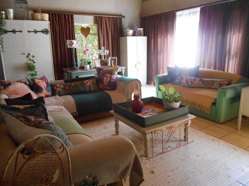 A comfortable living room featuring tiled flooring and large windows with curtain treatments, offering a bright and functional space for relaxation.