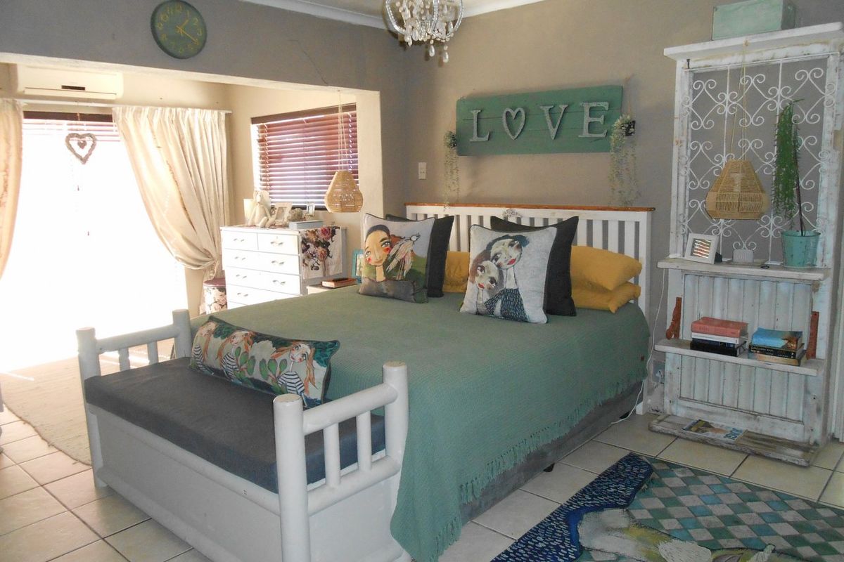 A bedroom featuring tiled flooring, a wall-mounted air conditioning unit, and window blinds, with direct access to an adjoining space.