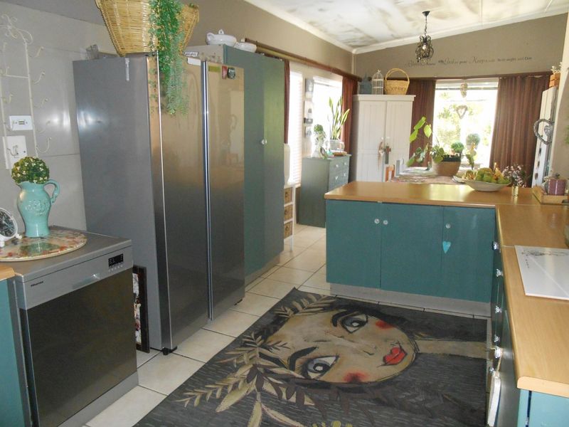 A kitchen area featuring built-in cabinetry and laminate countertops, with visible water staining on the ceiling requiring attention.