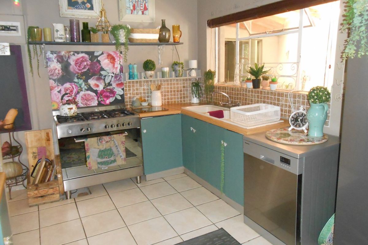 A functional kitchen featuring a gas stove, tiled backsplash, double sink, and ample built-in cabinetry with tiled flooring.