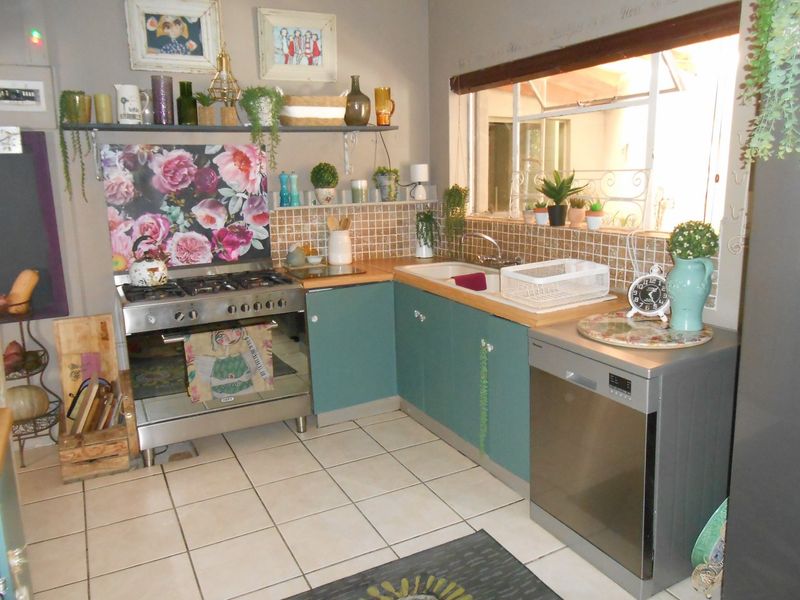 A functional kitchen featuring a gas stove, tiled backsplash, double sink, and ample built-in cabinetry with tiled flooring.