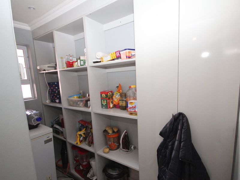 A functional scullery or pantry area featuring extensive built-in white shelving and cabinetry for organized storage.