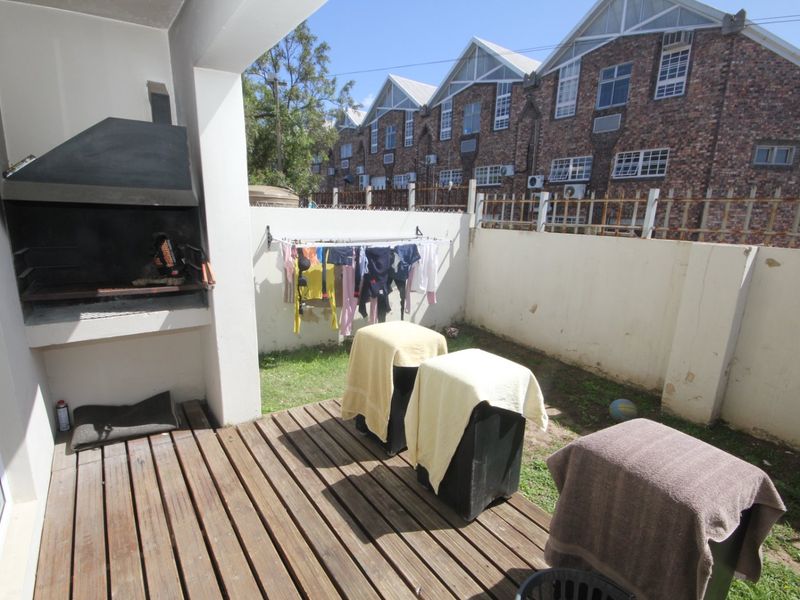 Outdoor patio area featuring timber decking and a built-in braai, providing a functional space for outdoor cooking and relaxation.