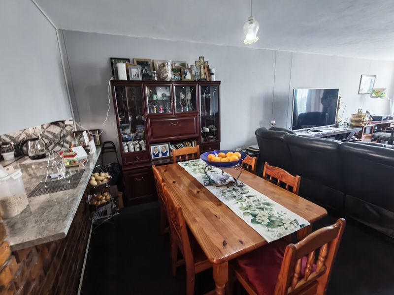 Open-plan living and dining area featuring a kitchen breakfast bar with stone-look countertop and brick detailing, creating a functional, combined living space.