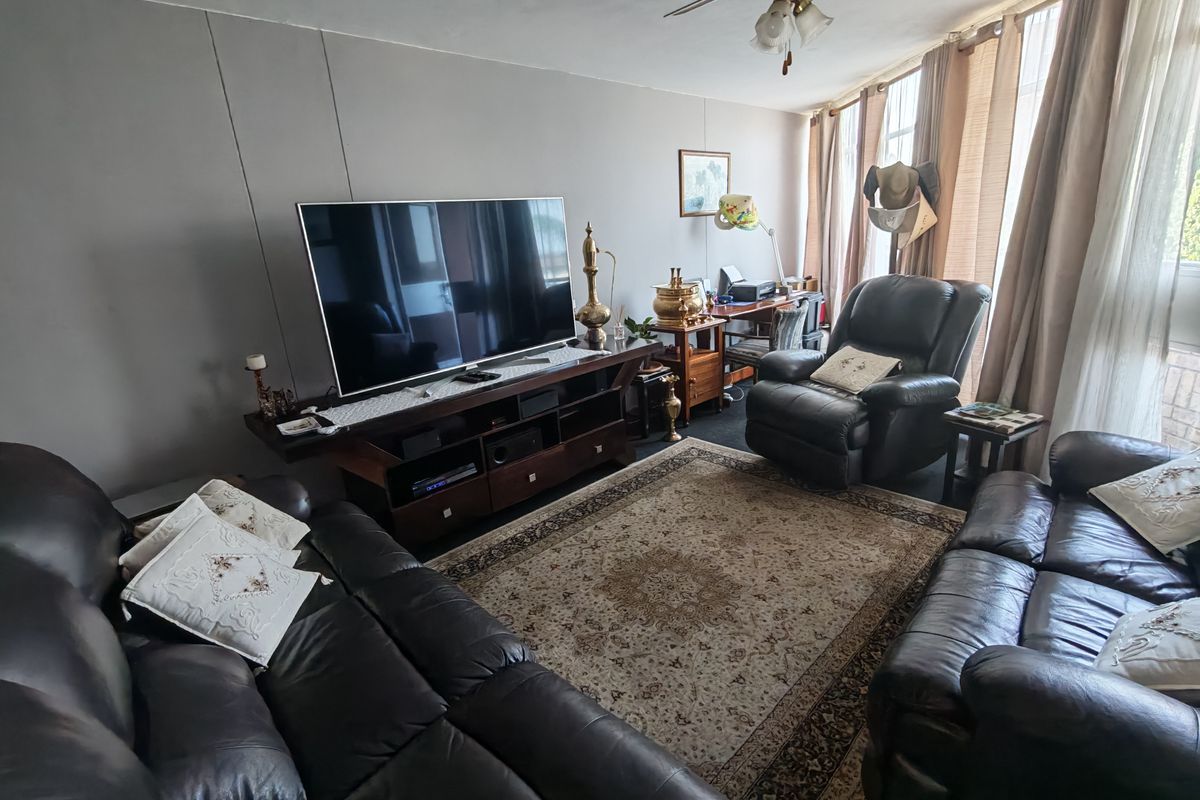 A spacious living room featuring a ceiling fan and large windows with natural light, offering a comfortable area for relaxation.