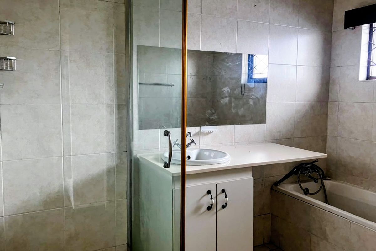 A functional bathroom featuring a vanity cabinet with integrated sink, a bathtub, and a separate shower enclosure with full-height wall tiling.