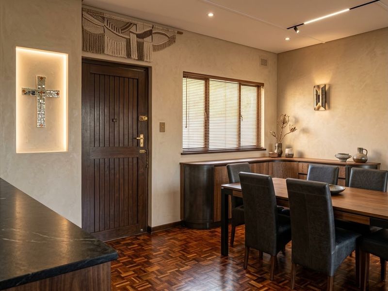 Elegant dining area featuring rich parquet flooring, custom built-in cabinetry, and sophisticated recessed wall lighting, creating a warm and inviting atmosphere.