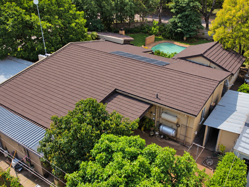 Aerial view of the property showing the tiled roof with solar panels, a swimming pool in the rear garden, and external utility installations.