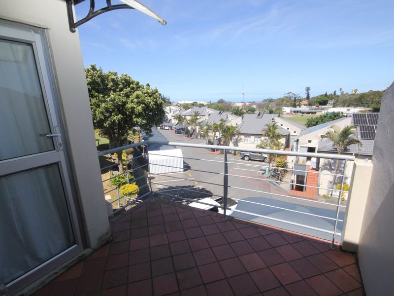 A private balcony featuring tiled flooring and a metal balustrade, offering an elevated view over the surrounding residential complex.