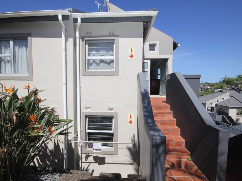 Exterior view of an apartment building featuring a terracotta tiled staircase leading to an upper-level entrance with aluminium framed windows.