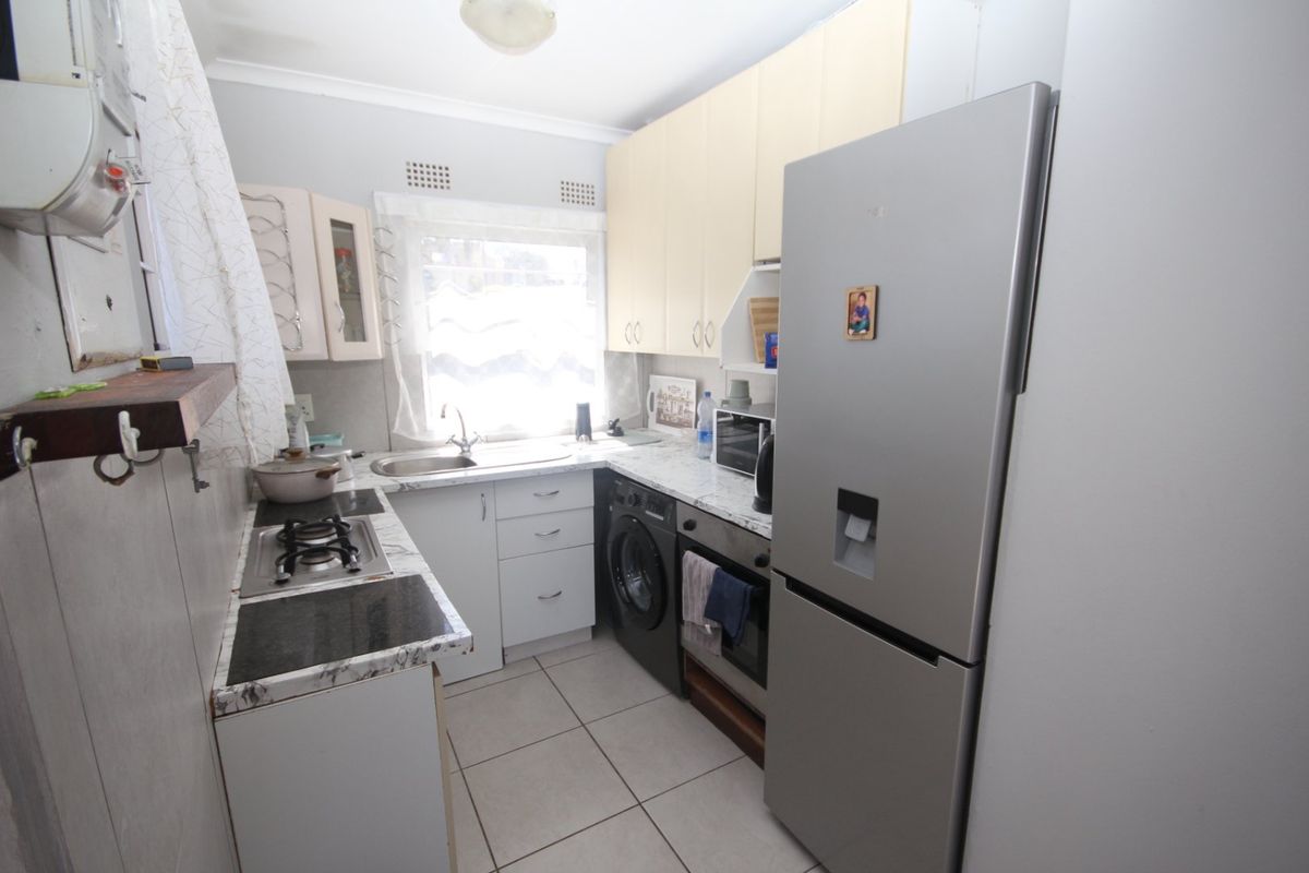 A functional kitchen featuring built-in cabinetry, laminate countertops, a gas hob, and tiled flooring, offering a practical layout for daily meal preparation.