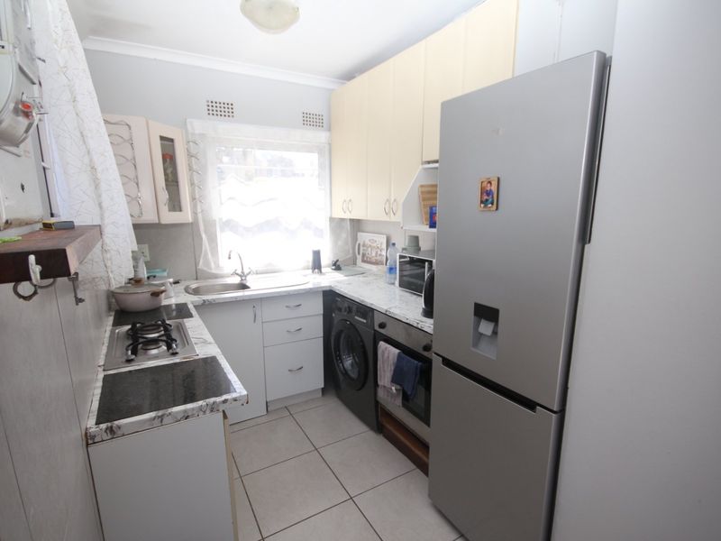 A functional kitchen featuring built-in cabinetry, laminate countertops, a gas hob, and tiled flooring, offering a practical layout for daily meal preparation.