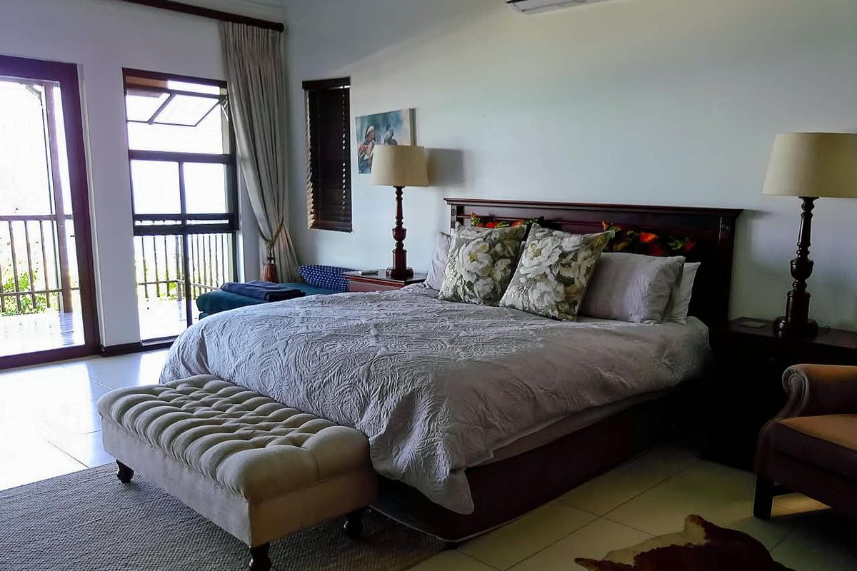 Spacious bedroom featuring tiled flooring, a wall-mounted air conditioning unit, and direct access to a private balcony through sliding glass doors.
