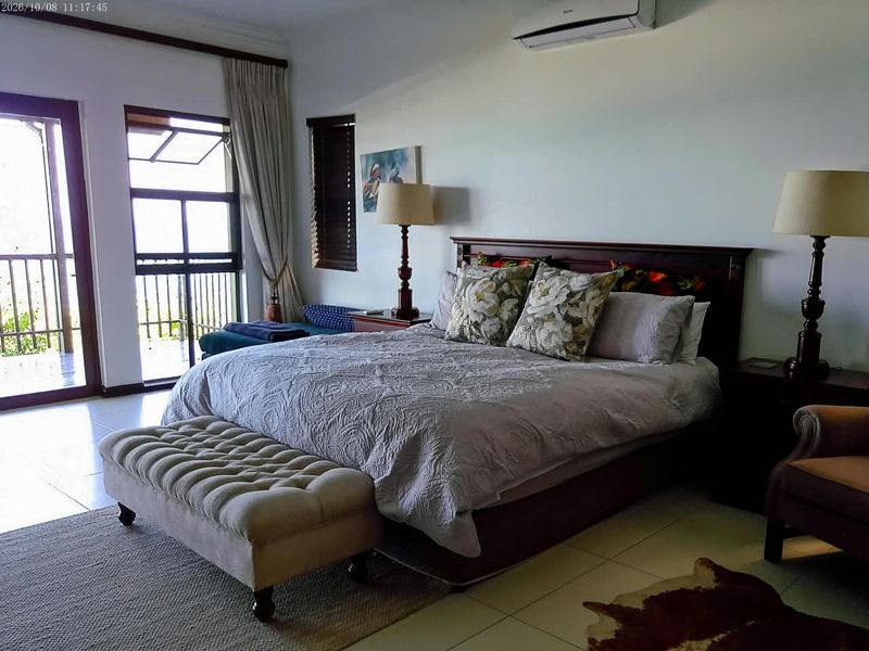 Spacious bedroom featuring tiled flooring, a wall-mounted air conditioning unit, and direct access to a private balcony through sliding glass doors.