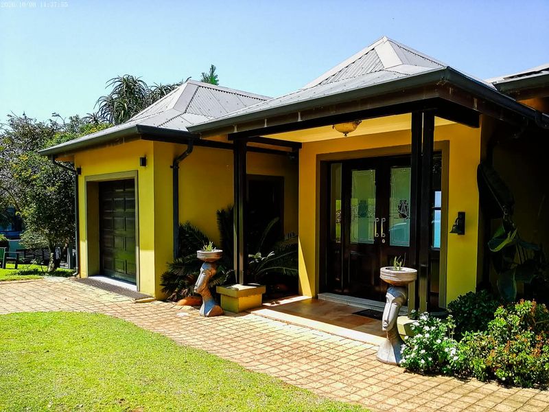 Front elevation of a house featuring a covered entrance, paved driveway, and integrated garage with a metal roof.
