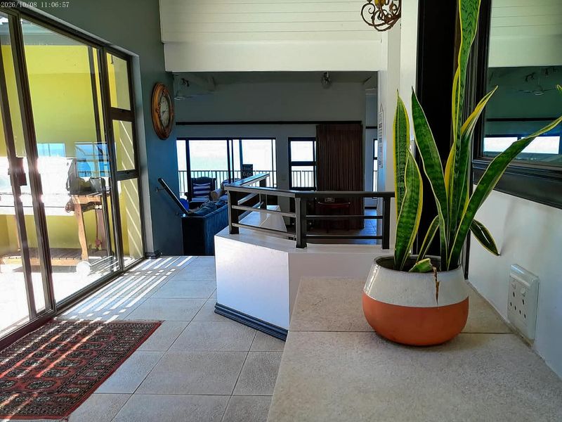An open-plan living area featuring tiled floors, a metal balustrade, and large sliding glass doors that provide natural light and access to the exterior.