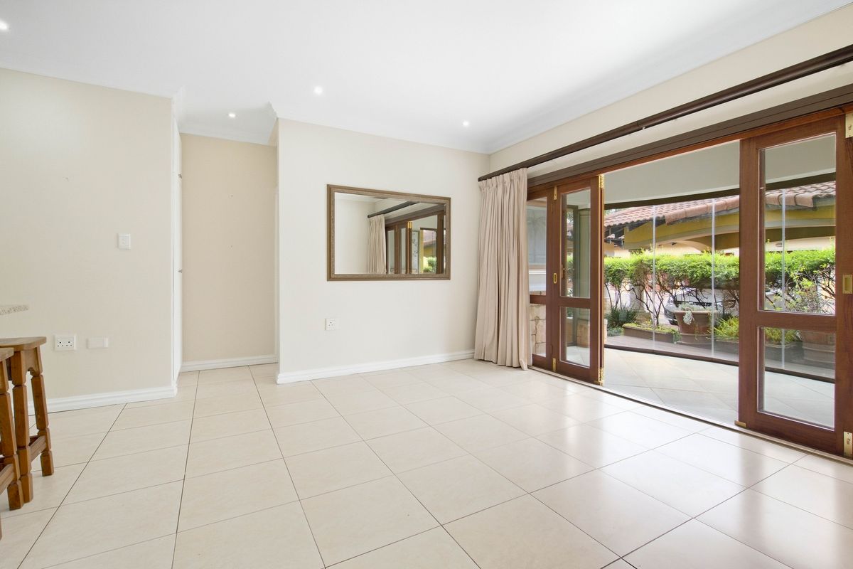 Spacious living area featuring neutral tiled flooring, recessed downlights, and large sliding timber doors providing seamless access to the outdoor patio area.