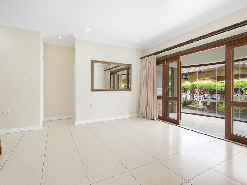 Spacious living area featuring neutral tiled flooring, recessed downlights, and large sliding timber doors providing seamless access to the outdoor patio area.