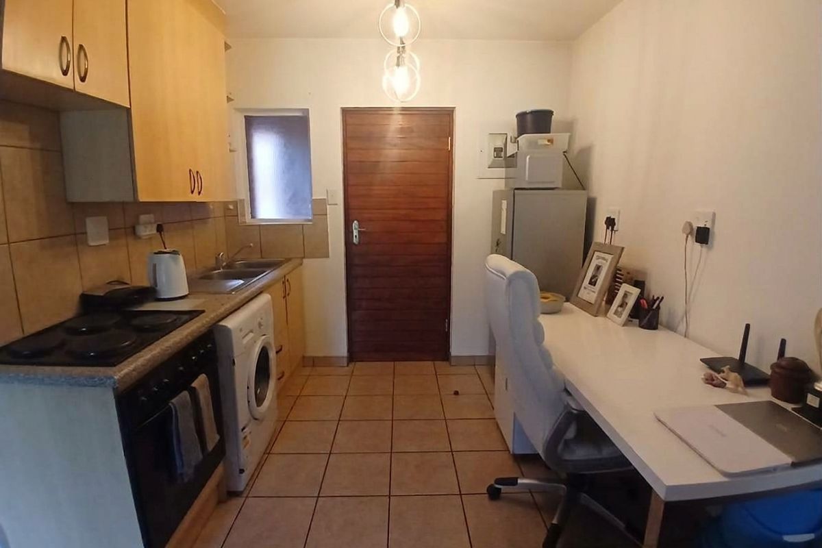 Compact kitchen featuring built-in cabinetry, electric hob, oven, and tiled flooring, providing a functional workspace with integrated laundry plumbing.