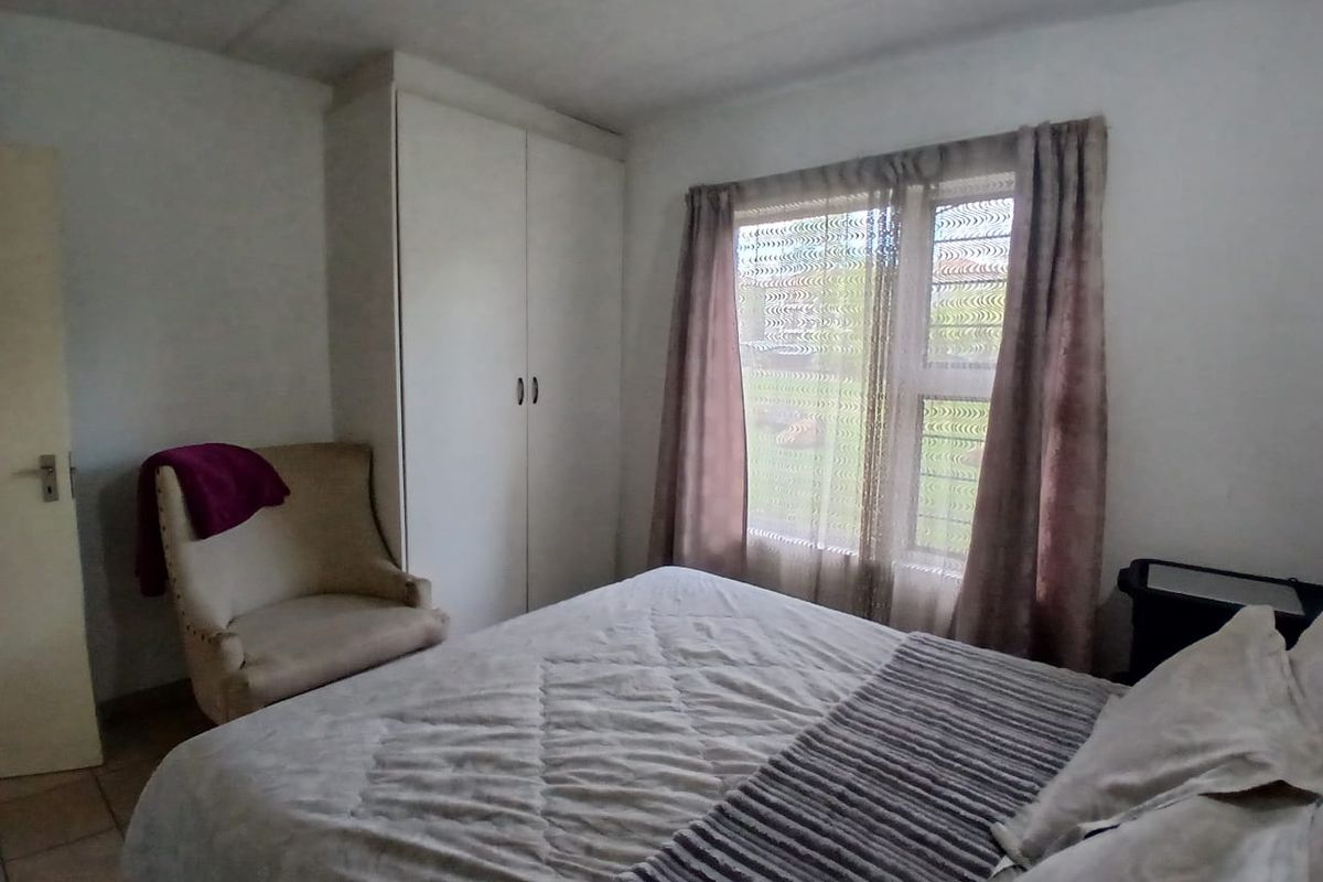 A functional bedroom featuring tiled flooring and a built-in wardrobe, offering a neutral space ready for personalization.