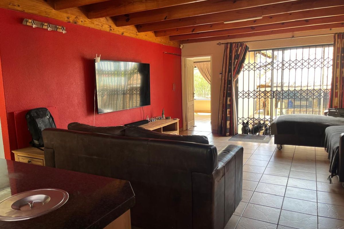 Spacious living area featuring exposed timber ceiling beams, tiled flooring, and direct access to the outdoor area through a secure sliding door.